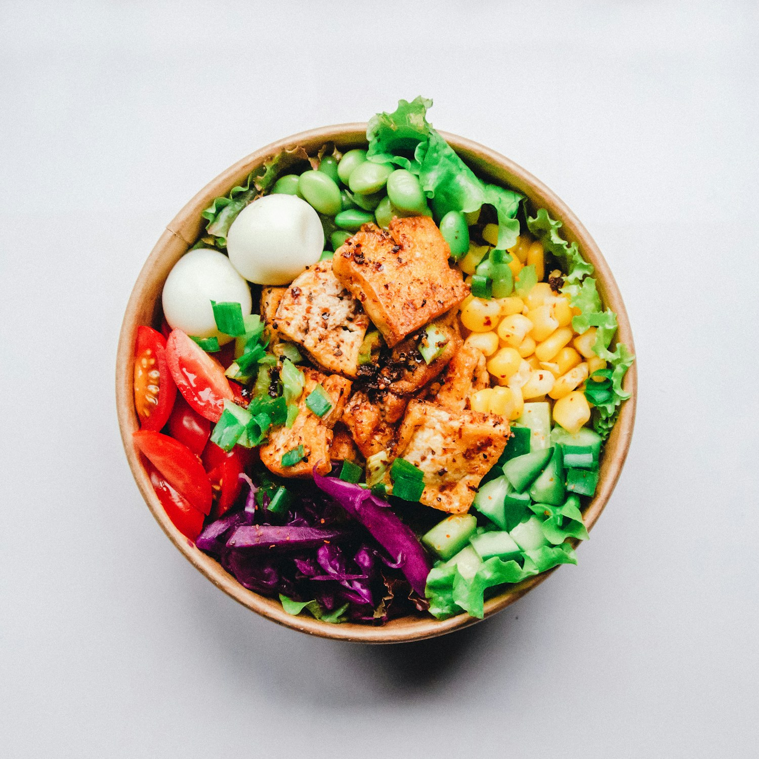 A colorful bowl of vegetables, greens, and tofu